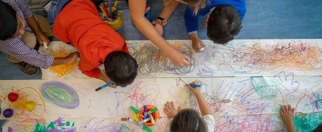 children drawing on long sheets of paper