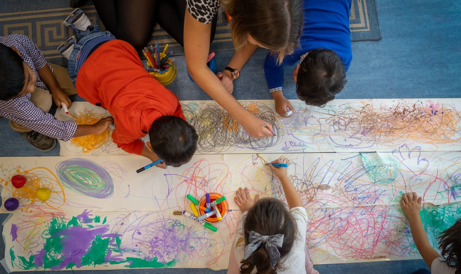 children drawing on long sheets of paper