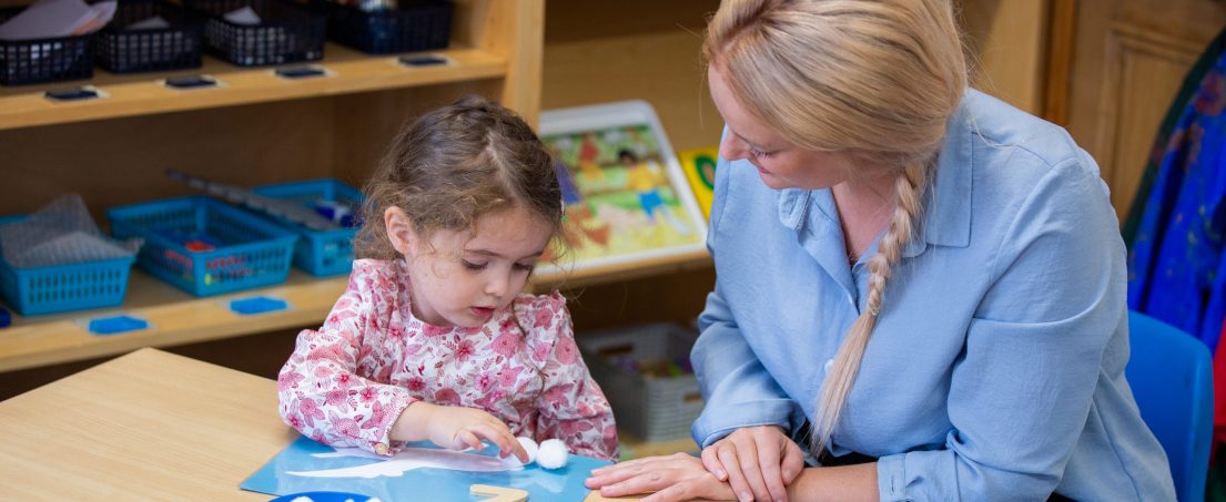 teacher and child looking at arts and crafts