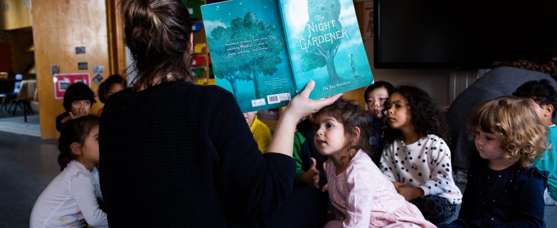 teacher holding up a book called the Night Gardener